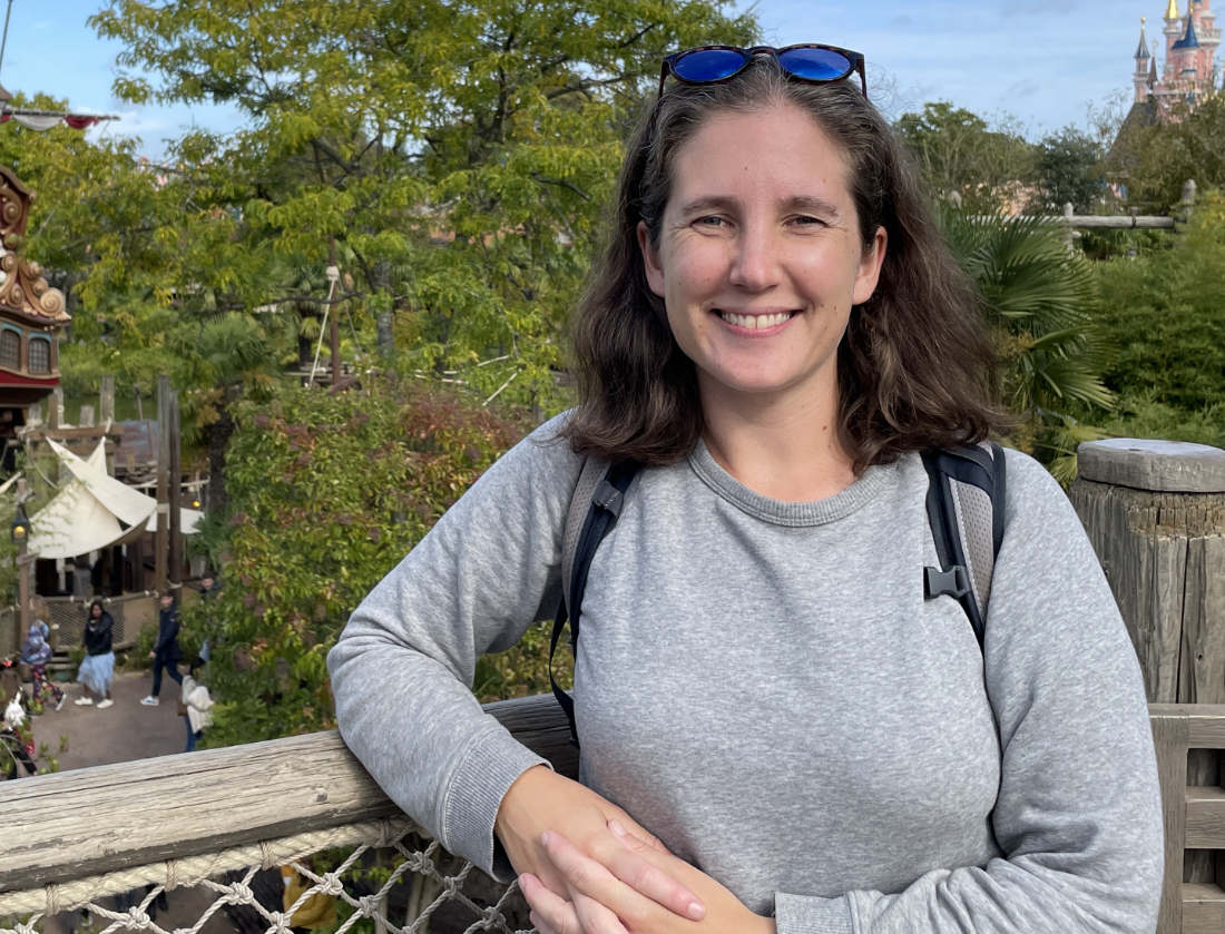 A photograph of Emily O'Neill leaning against a railing and smiling.